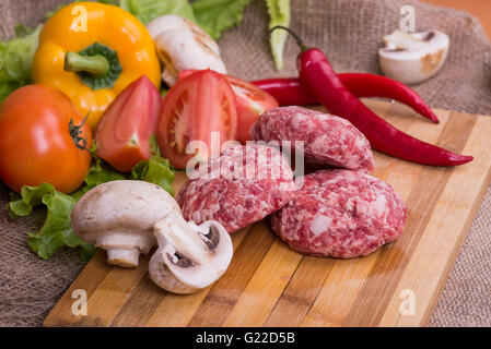 Crudo fresco cotoletta con le erbe aromatiche e i pomodori, funghi, peperoni Foto Stock