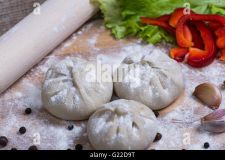 Pila di greggio in casa gnocchi di khinkali closeup con verdure sulla scheda Foto Stock