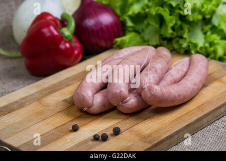 Salumi crudi con le verdure sul tagliere di legno Foto Stock