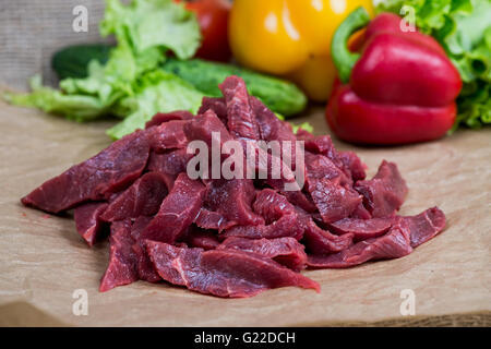 Crudo fresco manzo tritato, le spezie e le erbe su una luce sullo sfondo di legno Foto Stock