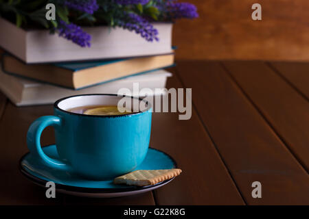 Tazza di tè con limone e vecchi libri su vintage sfondo di legno Foto Stock