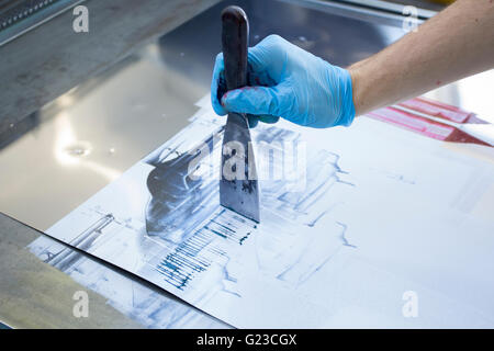 Artista utilizzando una tavolozza di coltello e oli su una superficie di acciaio inossidabile Foto Stock