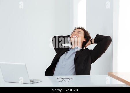 Happy businessman in appoggio al suo luogo di lavoro in ufficio Foto Stock