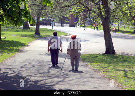 Persone di mezza età o vecchio giovane con bastone da passeggio a piedi in Kelvingrove Park, Glasgow, Scotland, Regno Unito. Foto Stock