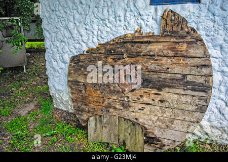 Vecchio danneggiato in legno piattaforma circolare appoggiata contro il muro della casa. Foto Stock