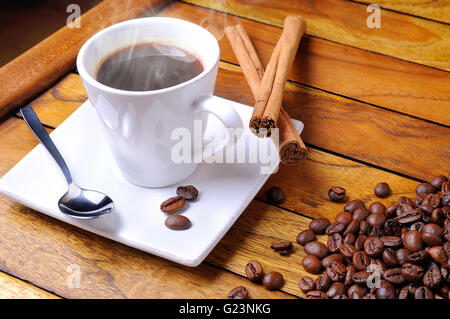 Tazza fumante di caffè in grani e gruppo su un marrone tavolo in legno Foto Stock