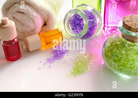 Gli oli e i sali da bagno in vetro bianco tabella dettaglio. Decorata con fiori e asciugamano. Composizione orizzontale Foto Stock