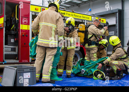 Vigili del fuoco assistere un collega don a tenuta di gas Suit durante un incidente chimico esercizio nel Kent. Foto Stock