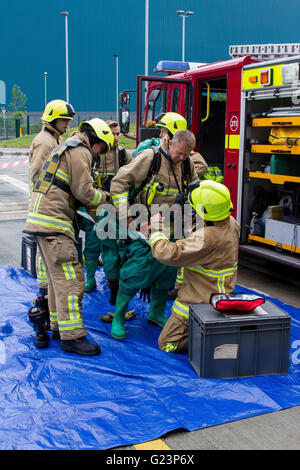 Vigili del fuoco assistere un collega don a tenuta di gas Suit durante un incidente chimico esercizio nel Kent. Foto Stock