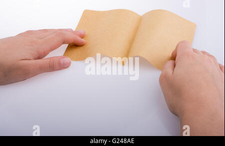 Mano che tiene un foglio di carta su uno sfondo bianco Foto Stock