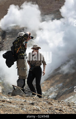 Escursionismo in Kamchatka - turisti fotografare e guardando la fumante (fumatori) fumarole sul cratere attivo vulcano Mutnovsky. Foto Stock