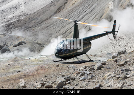 Touristic Elicottero Robinson R44 Raven con i viaggiatori e turisti a bordo in piedi da nel cratere attivo del vulcano Mutnovsky Foto Stock