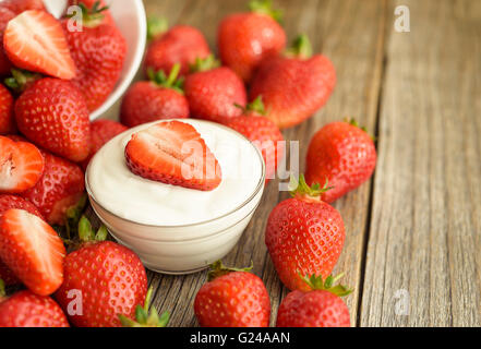Fragole tagliate in yogurt su tavole di legno. Close-up. Foto Stock