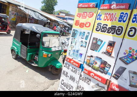 Tangalle , città nel distretto di Hambantota, sud della provincia, Sri Lanka, un tuk tuk rickshaw parcheggiato di fianco a un negozio di telefono Foto Stock