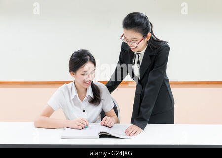 Guida per insegnanti qualcosa di studenti asiatici in uniforme in aula Foto Stock