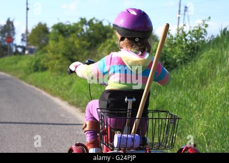 Bambina in sella a una di tre ruote moto di riabilitazione Foto Stock