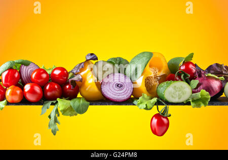 Mature succose verdure con foglie di insalata su sfondo giallo Foto Stock