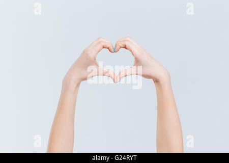 Mani femminili che mostra il gesto di cuore con dita isolato su uno sfondo bianco Foto Stock