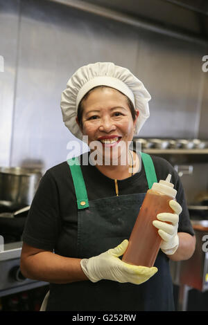 Donna asiatica chef tenendo la bottiglia di salsa Foto Stock
