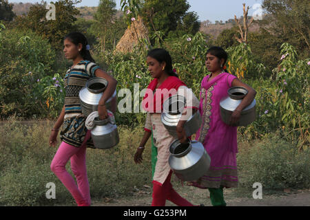 Eh tribù - ragazze che trasportano acqua vuoto pentole per riempire con acqua. Villaggio Londari, Maharashtra, India Foto Stock