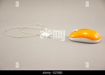 Mouse ottico,colore arancione su sfondo grigio. Foto Stock