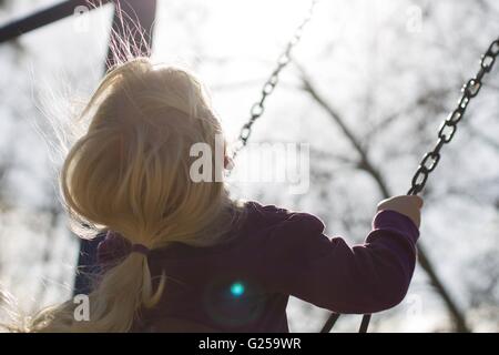 Vista posteriore di una ragazza seduta su un altalena Foto Stock