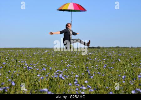 Bilanciamento del uomo ombrello sul mento mentre messing about in un campo, Niort, Francia Foto Stock