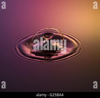 Water drop fotografia, una o due gocce di acqua è scesa da altezza in acqua e catturato in quanto colpiscono l'acqua o si scontrano w Foto Stock