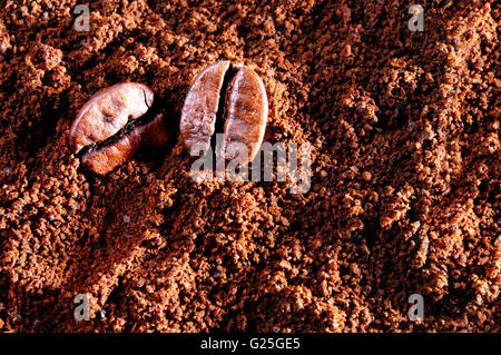 Due grani di caffè sullo sfondo di macinato di caffè vista superiore Foto Stock