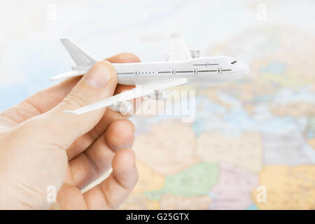 Viaggiando, turismo, comunicazioni e tutte le cose relative - Toy piano in mano con mappa del mondo sullo sfondo come un simbolo di aria t Foto Stock