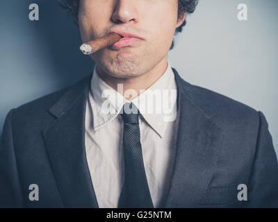 Un giovane imprenditore fiducioso sta fumando un sigaro Foto Stock