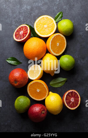 Fresche e mature agrumi. I Limoni e limette e le arance in pietra scura sullo sfondo. Vista superiore Foto Stock