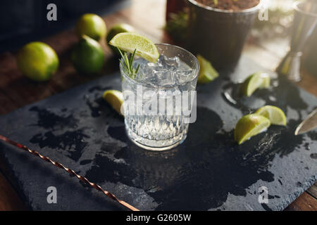 Close up appena fatti e gin tonic bevanda con le fette di limone e il cucchiaio su una scheda di colore nero. Foto Stock