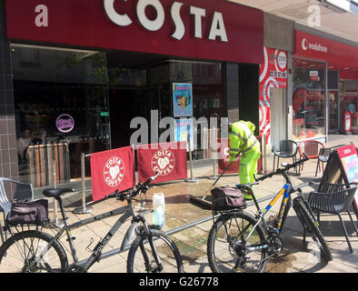 Portsmouth, Hampshire, Regno Unito. Xxiv Maggio, 2016. Un paio di questo pomeriggio sono in recupero dopo un negozio di fronte nella trafficata strada commerciale in Portsmouth è caduto e ha bussato al suolo al di fuori della Costa Coffee. La mezza età giovane necessario il trattamento in ospedale dopo un grande pezzo di negozio di fronte è caduto a terra ed ha battuto fuori. Un occhio-testimonianza, ha detto, "è stato scioccante. Ero seduto vicino a quando ho visto il legno cadere dalla parte superiore e il giovane è sprofondato in un heap nel terreno. Credito: uknip/Alamy Live News Foto Stock