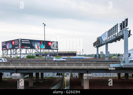 La sezione sollevata dell'autostrada M6 con la rotazione del gantry e il livello elevato della pubblicità elettronica billboard al crepuscolo, Bescot, Walsall, West Midlands, England, Regno Unito Foto Stock