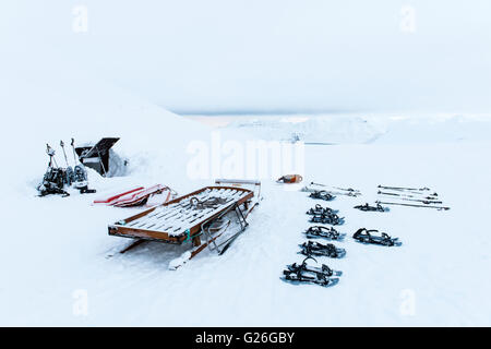 Attrezzatura da sci all'ingresso della caverna di ghiaccio con montagne innevate Longyearbyen, Svalbard, Spitsbergen, Norvegia Foto Stock