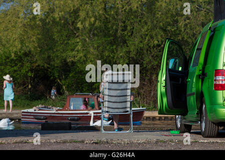 La donna si siede nella sedia sdraio a guardare i visitatori del fine settimana sul fiume Bure a Wroxham Foto Stock