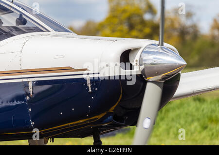 Una tenuta di close-up del naso e propulsore di un Piper PA-28, con una leggera sfocatura sull'elica Elstree Airfield, Herts UK Foto Stock