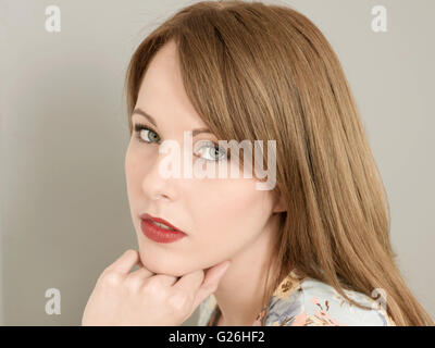 Ritratto di un ragionato interessati preoccupato giovane donna guardando la telecamera in appoggio la sua testa sul suo mento Foto Stock