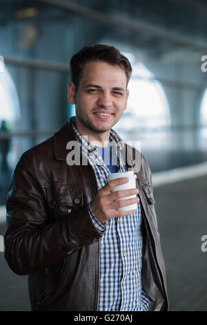 Outdoor ritratto della moderna giovane con caffè di andare cup, sorridente Foto Stock
