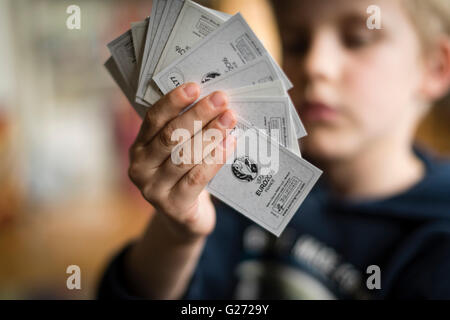 Un bambino di 8 anni è il ragazzo che mostra il suo calcio Panini scambio di carte prima di incollare nella sua sticker collection scrapbook. Foto Stock