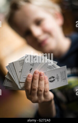 Un bambino di 8 anni è il ragazzo che mostra il suo calcio Panini scambio di carte prima di incollare nella sua sticker collection scrapbook. Foto Stock