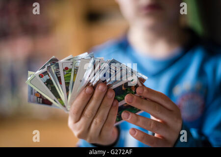 Un bambino di 8 anni è il ragazzo che mostra il suo calcio Panini scambio di carte prima di incollare nella sua sticker collection scrapbook. Foto Stock