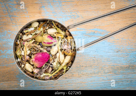 Mesuring scoop di pelle sana tè alle erbe, una miscela di rosso bocciolo di rosa. pesca fiore, lavanda, rosmarino, caprifoglio Foto Stock