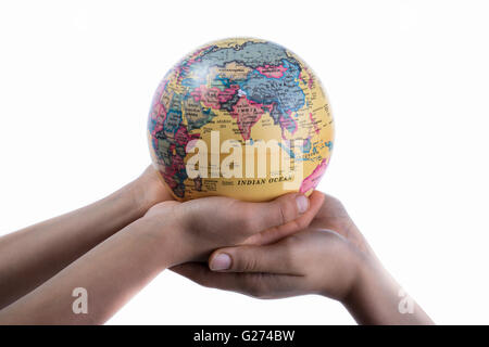 Due mani tenendo un globo in mano su sfondo bianco Foto Stock