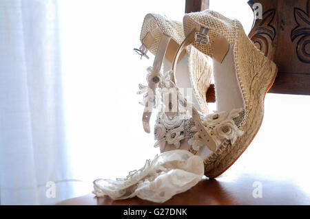 Bianco scarpe matrimonio posto su una sedia in una stanza Foto Stock