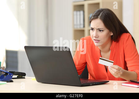 Acquirente Casual preoccupato con problemi acquisti on line con la carta di credito e un computer portatile in un piccolo ufficio o a casa Foto Stock