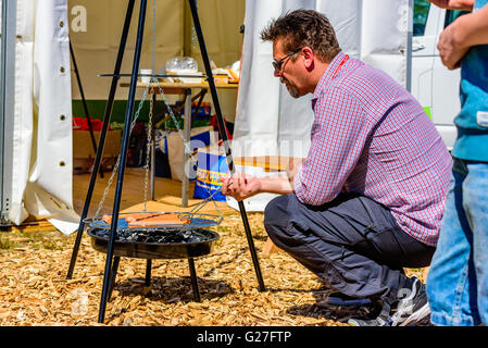 Emmaboda, Svezia - 13 Maggio 2016: la foresta e il trattore (Skog och traktor) fiera. Addetto alle vendite la grigliatura alcuni hot dogs per i visitatori Foto Stock