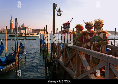 Carnevale di Venezia: San Marco, Venezia, Italia. Di fronte al Bacino di San Marco, con la chiesa di San Giorgio maggiore oltre, si trovano i festaioli del Carnevale Foto Stock