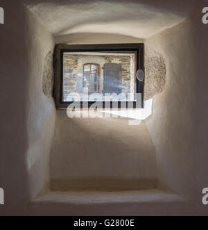 Visualizzazione di una finestra di legno e otturatore attraverso un'altra finestra in una pietra thinck e rendere la parete in gesso con il sole che splende attraverso, Francia Foto Stock